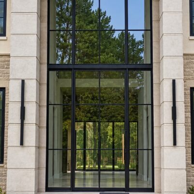 Modern home entrance with tall glass windows and stone columns.