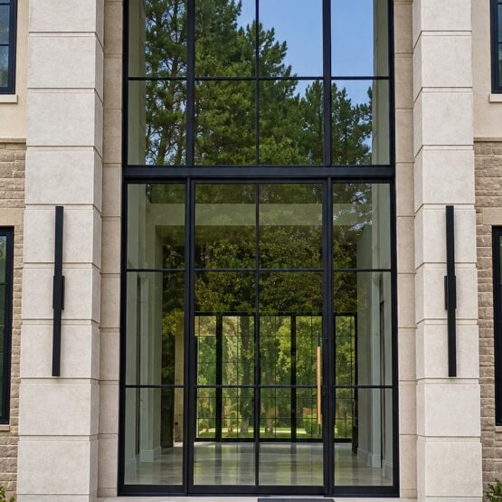 Modern home entrance with tall glass windows and stone columns.
